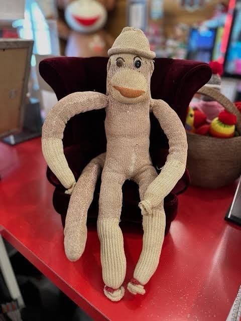 The real Luno, a worn handmade sock monkey in a small velvet chair